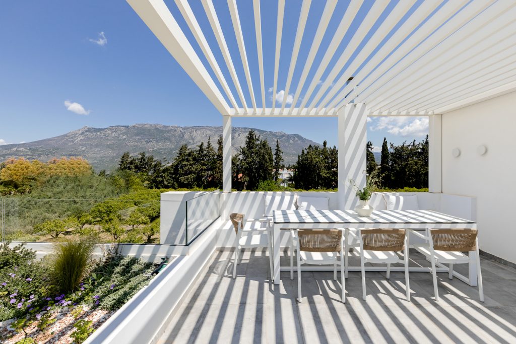 Βεράντα με λευκή πέργκολα και υπαίθρια τραπεζαρία